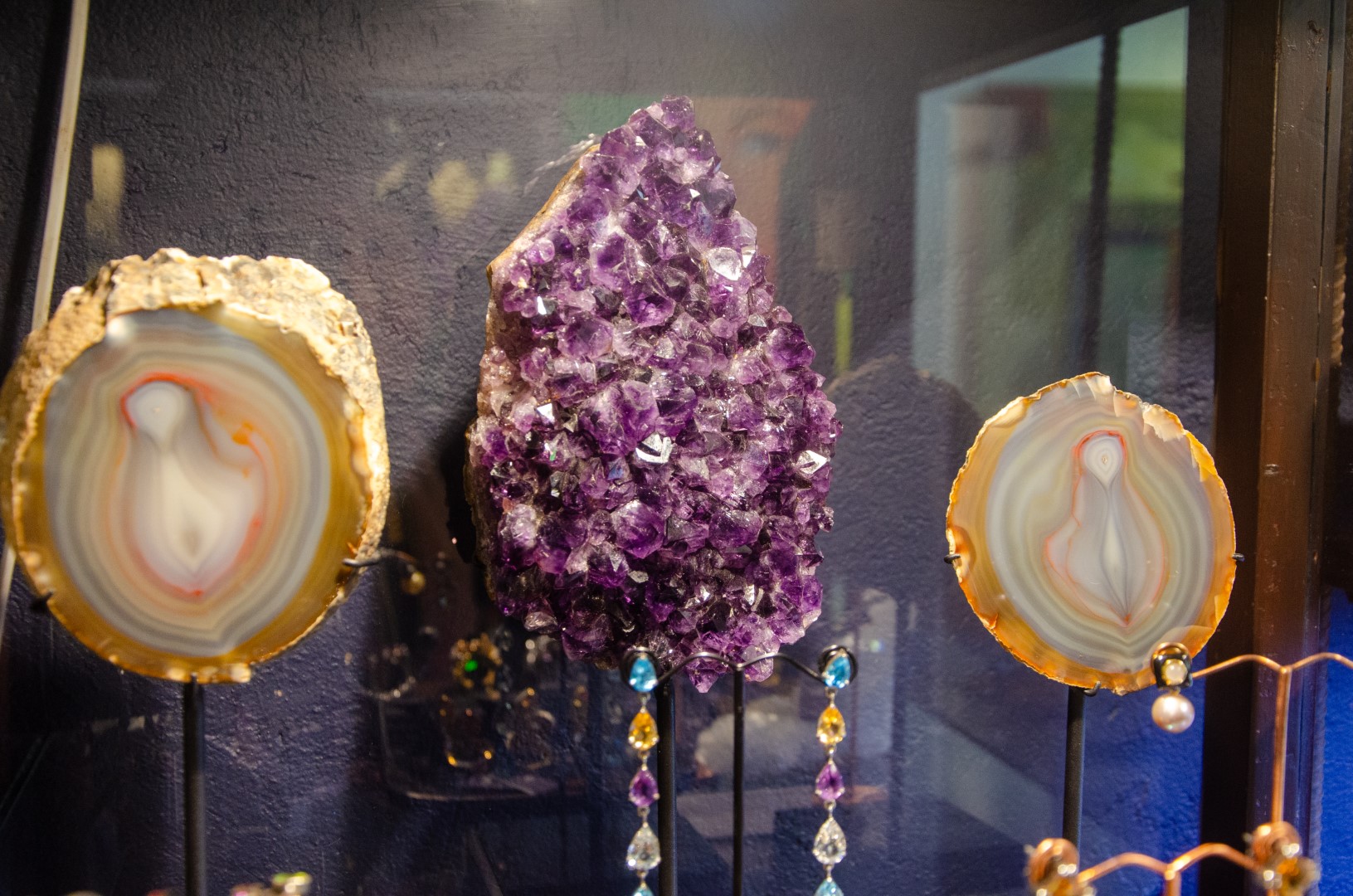 Agate slices and an amethyst cluster mounted on iron stands at Fe2