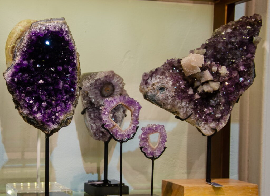 Amethyst geodes and slices of different sizes on metal stands