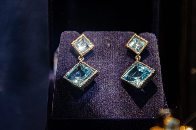 Square blue stone earrings on a navy display pad