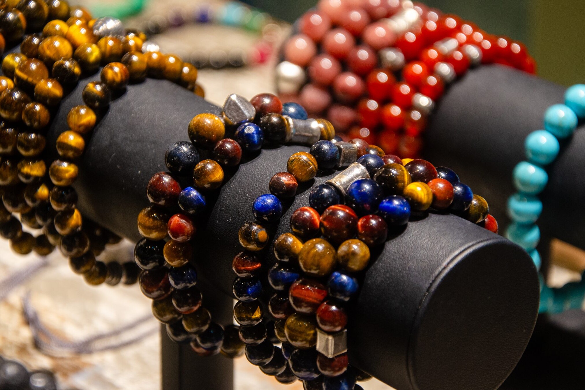 Stone bead bracelets in brown, red, blue and turquoise tones on display rolls
