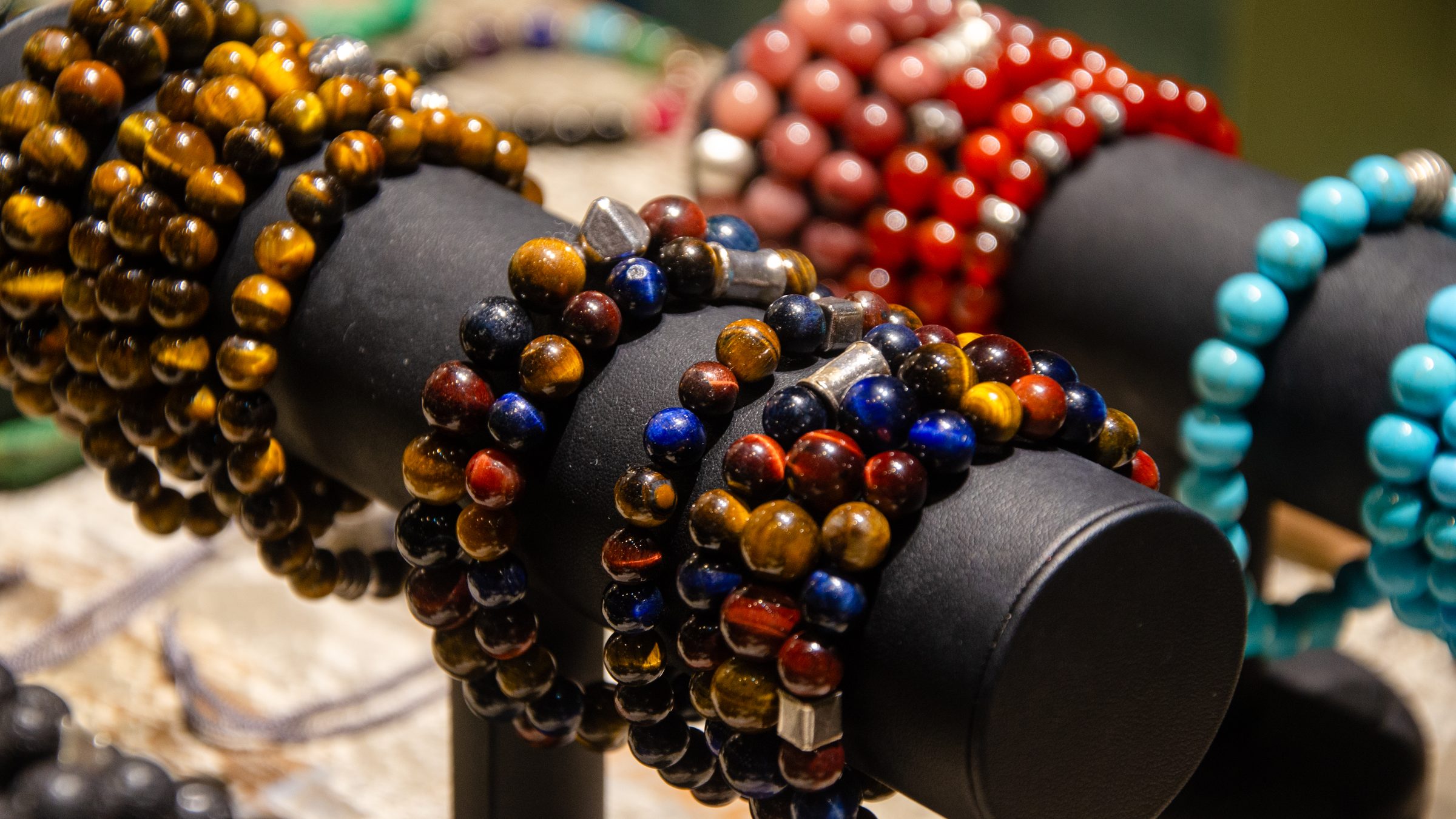 Stone bead bracelets in brown, red, blue and turquoise tones on display rolls