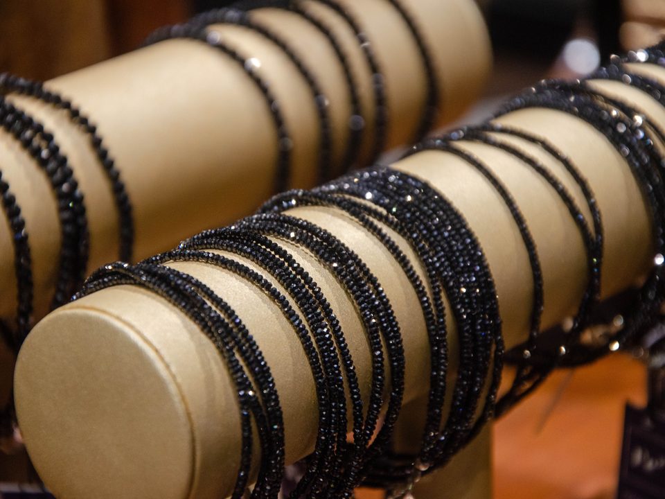 Black bead bracelets stacked on a cream display stand