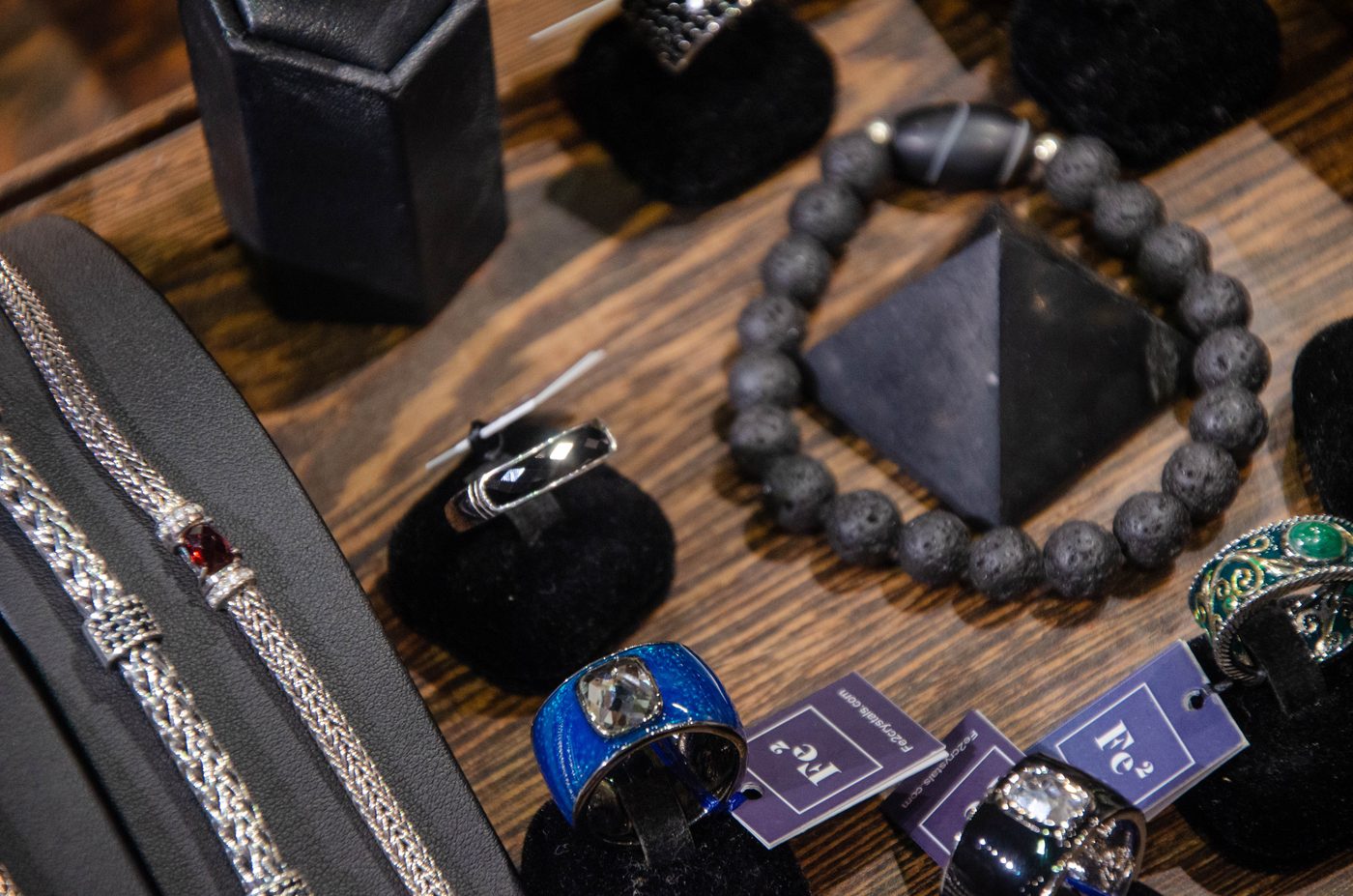 Bead and chain bracelets with rings on a dark wooden table