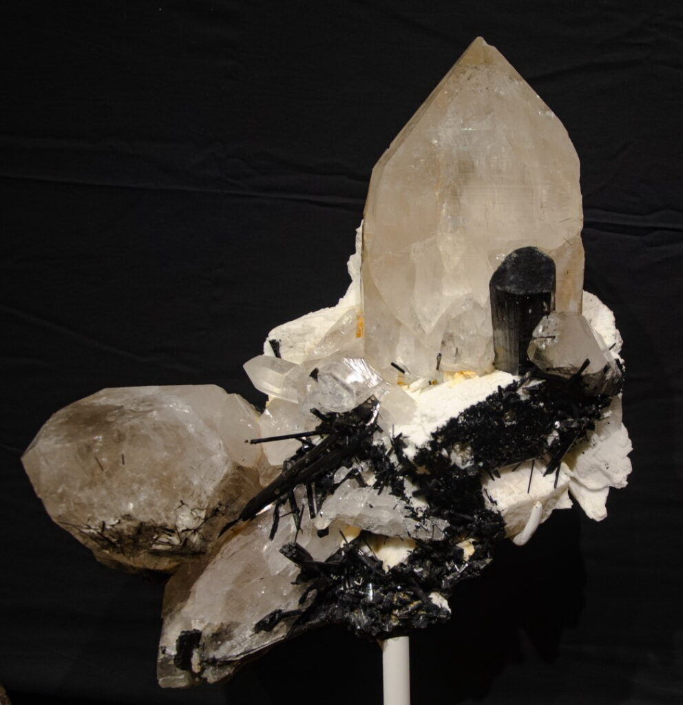 Clear quartz crystals with black needle-like crystals on a white base